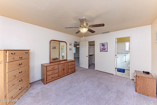 carpeted bedroom featuring ceiling fan, ensuite bathroom, a textured ceiling, a spacious closet, and a closet