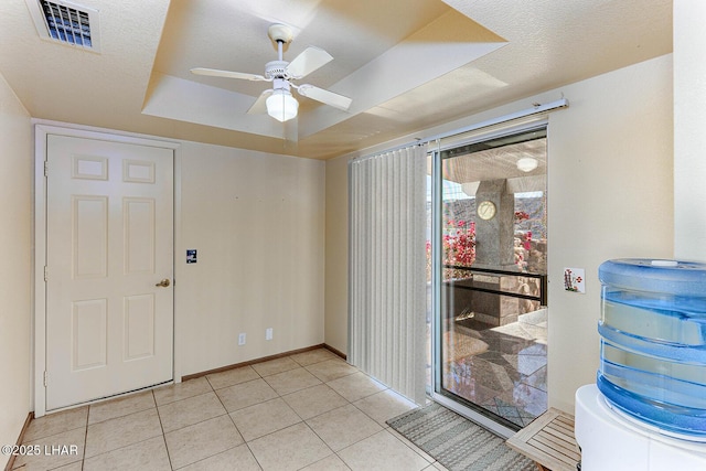 interior space with a raised ceiling, light tile patterned floors, a textured ceiling, and ceiling fan