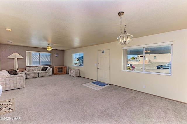 unfurnished living room with carpet flooring, ceiling fan with notable chandelier, and a textured ceiling