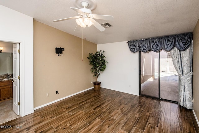 empty room featuring ceiling fan, dark hardwood / wood-style floors, sink, and a textured ceiling