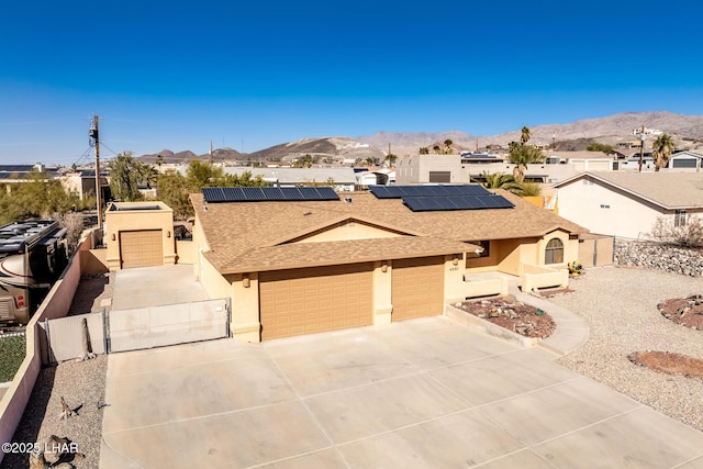 view of front of property with a garage, a mountain view, and solar panels