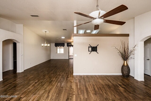 unfurnished living room with ceiling fan with notable chandelier, dark hardwood / wood-style floors, and vaulted ceiling