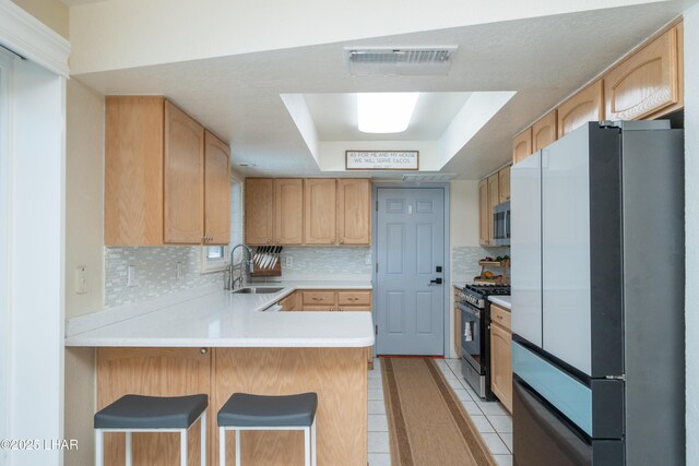 913 Thunderbolt Ave, Lake Havasu City, AZ 86406 - kitchen featuring freestanding refrigerator, range with gas stovetop, a tray ceiling, a peninsula, and tasteful backsplash