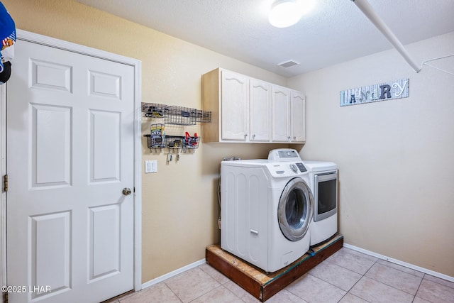 washroom featuring light tile patterned floors, baseboards, cabinet space, and washing machine and clothes dryer