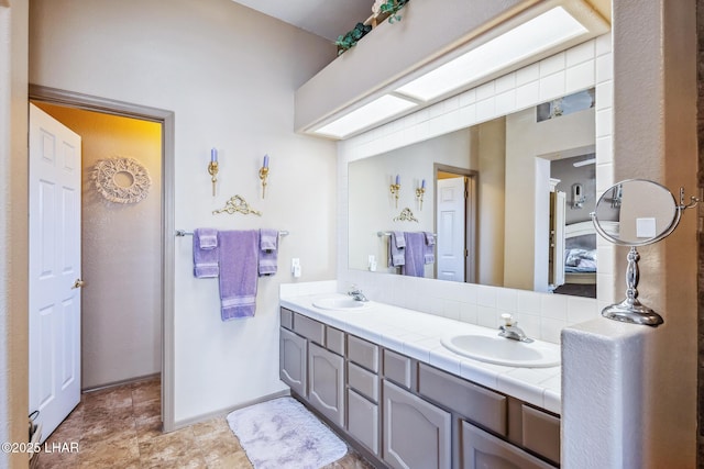 bathroom featuring double vanity, a sink, and baseboards