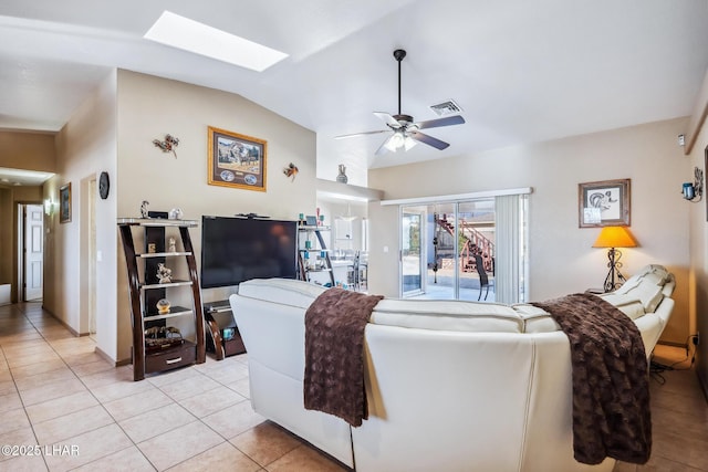 living area featuring light tile patterned floors, ceiling fan, vaulted ceiling with skylight, and visible vents