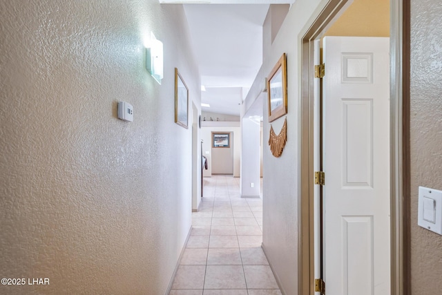 hallway with a textured wall and light tile patterned floors