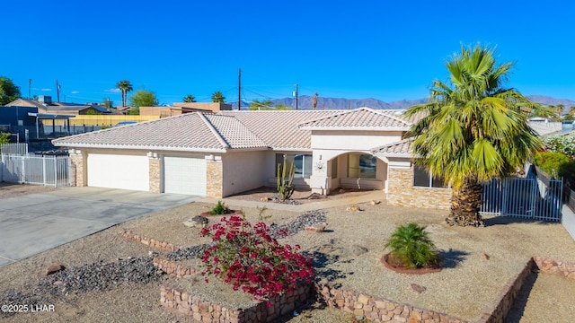 view of front of house featuring a tile roof, fence, a mountain view, an attached garage, and stucco siding