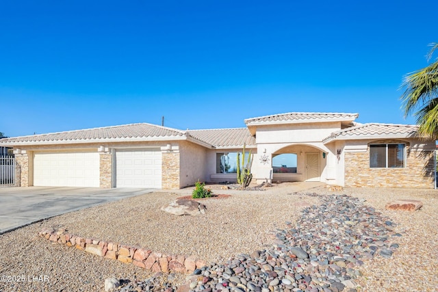 view of front of property with a tiled roof, a garage, concrete driveway, stone siding, and stucco siding