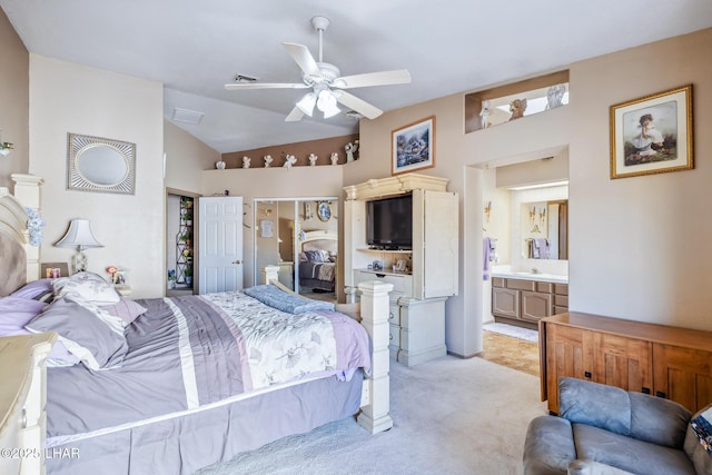 bedroom with a ceiling fan, ensuite bathroom, light colored carpet, a sink, and vaulted ceiling