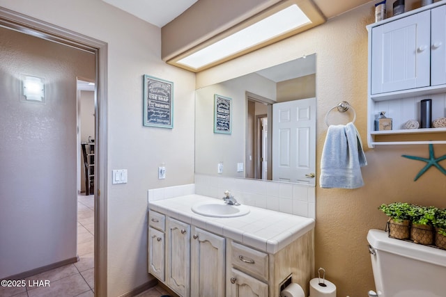 bathroom with toilet, tile patterned floors, and vanity