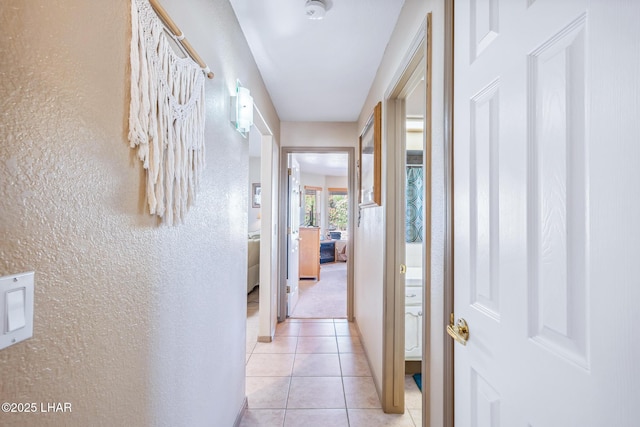 hallway featuring a textured wall and light tile patterned floors