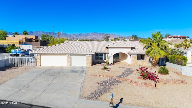view of front of property featuring a tiled roof, driveway, fence, a mountain view, and an attached garage