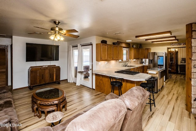 living room featuring ceiling fan, sink, and light hardwood / wood-style floors