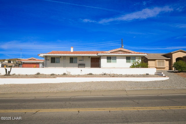 view of front facade featuring stucco siding, a fenced front yard, and a tiled roof