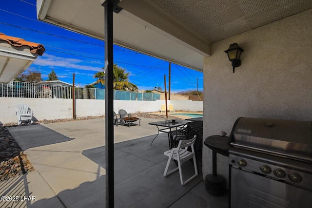 view of patio with a fenced in pool, an outdoor fire pit, a fenced backyard, and grilling area