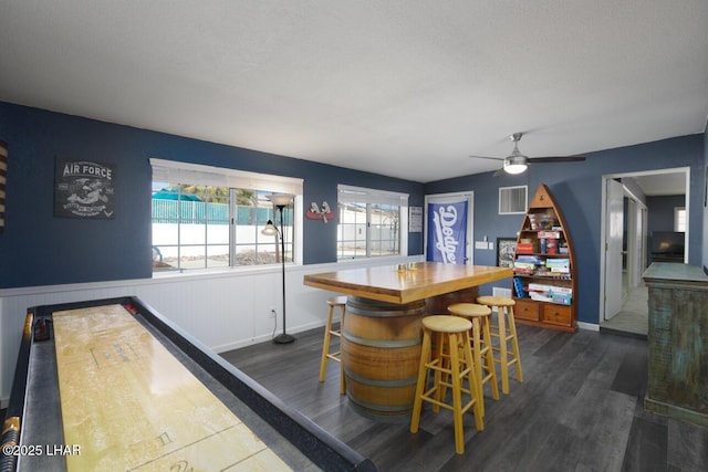 bar with dark wood-type flooring, a wainscoted wall, visible vents, and a dry bar