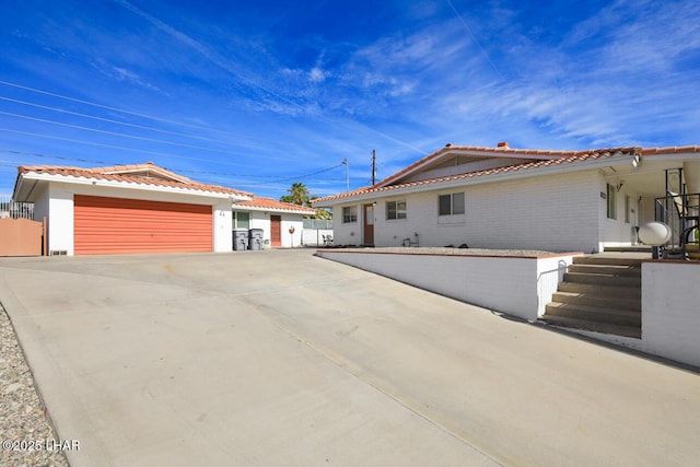 single story home with a garage, brick siding, and a tiled roof