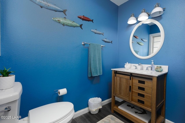 bathroom with wood finished floors, vanity, toilet, and baseboards