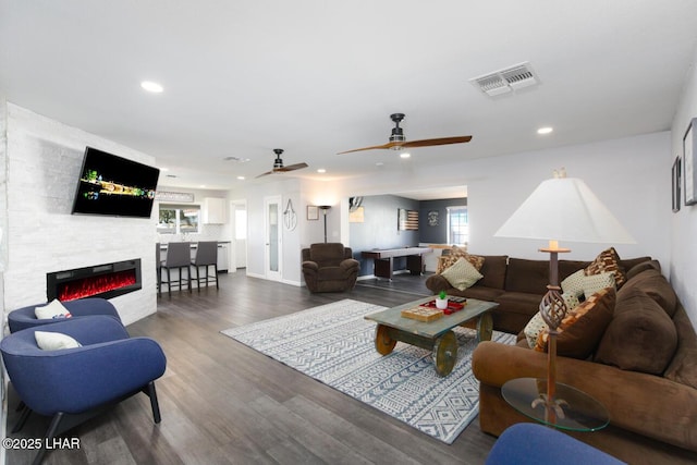 living room featuring a fireplace, visible vents, dark wood-style flooring, and recessed lighting