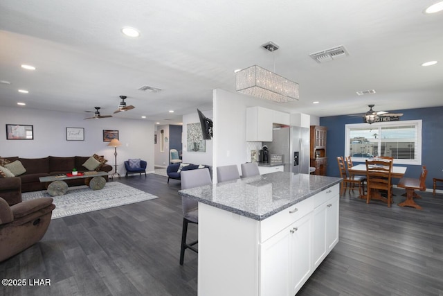 kitchen featuring light stone counters, open floor plan, white cabinetry, and stainless steel refrigerator with ice dispenser