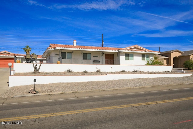 ranch-style house featuring a fenced front yard, a tile roof, and a chimney