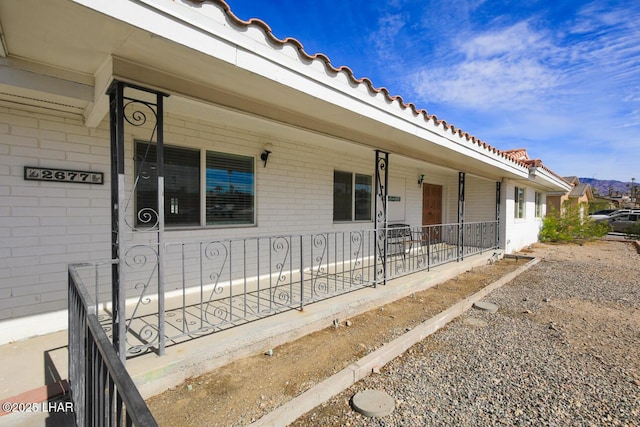 view of exterior entry featuring a tiled roof and brick siding