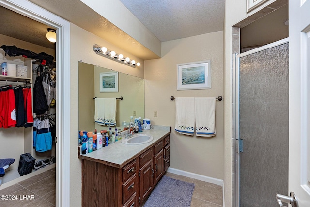 bathroom with vanity, tile patterned flooring, a shower with door, and a textured ceiling