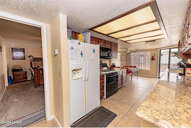 kitchen with range with gas cooktop, sink, white fridge with ice dispenser, light tile patterned floors, and a textured ceiling