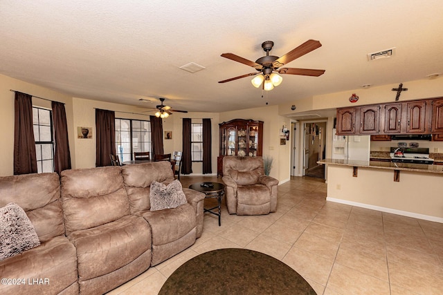 tiled living room with a textured ceiling and ceiling fan