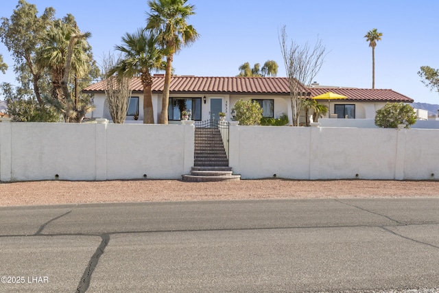 view of front of home featuring a fenced front yard, stairway, stucco siding, and a tiled roof