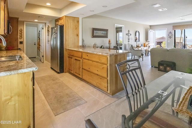 kitchen featuring light tile patterned flooring, stainless steel appliances, light stone counters, and sink