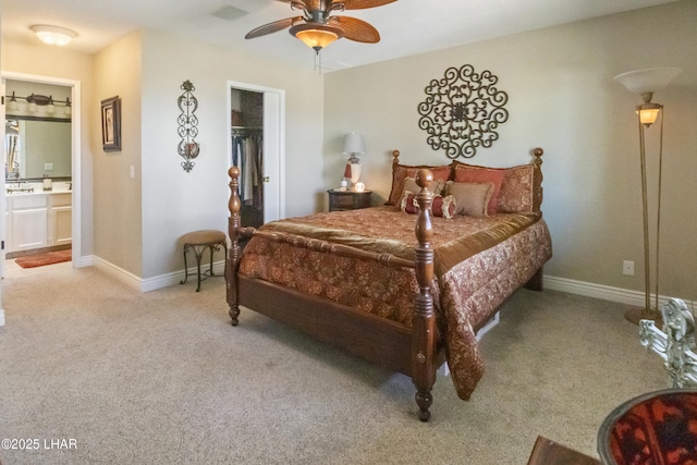 bedroom featuring ceiling fan, ensuite bathroom, light colored carpet, and a spacious closet