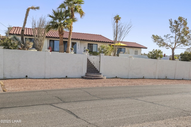 view of front of property with a tiled roof, a fenced front yard, a gate, and stucco siding