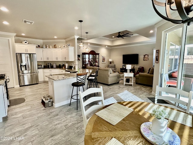 kitchen with sink, decorative light fixtures, stainless steel fridge with ice dispenser, kitchen peninsula, and white cabinets