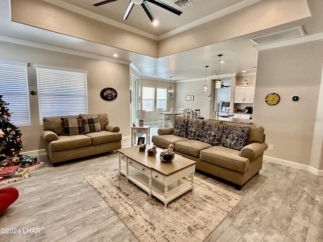 living room with crown molding, ceiling fan, and light wood-type flooring