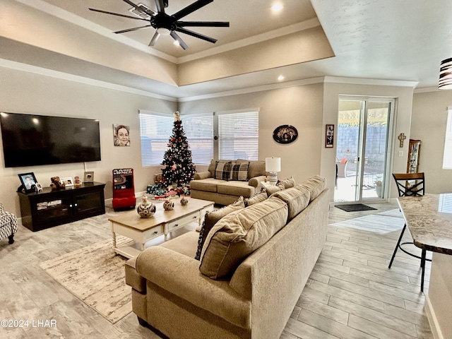 living room with ornamental molding, a tray ceiling, and light hardwood / wood-style flooring