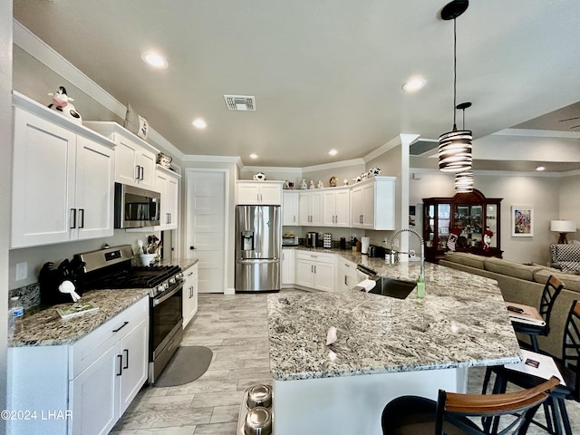 kitchen with sink, hanging light fixtures, appliances with stainless steel finishes, kitchen peninsula, and light stone countertops