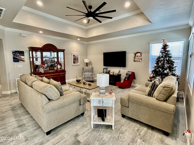 living room featuring crown molding, a raised ceiling, and light hardwood / wood-style flooring