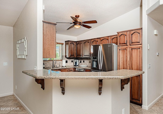 672 Wayside Dr, Lake Havasu City, AZ 86403 - kitchen featuring ceiling fan, a breakfast bar area, a peninsula, tasteful backsplash, and light tile patterned floors