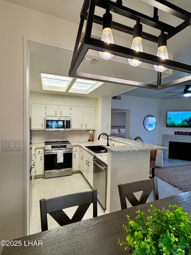 1650 S Smoketree Ave Unit 116, Lake Havasu City, AZ 86403 - kitchen with appliances with stainless steel finishes, a sink, a peninsula, white cabinets, and light tile patterned floors