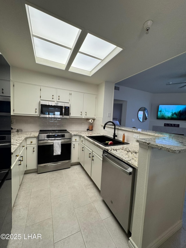 1650 S Smoketree Ave Unit 116, Lake Havasu City, AZ 86403 - kitchen featuring appliances with stainless steel finishes, a sink, tasteful backsplash, a skylight, and a peninsula