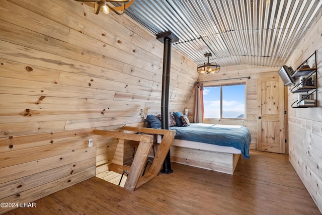 bedroom with hardwood / wood-style flooring, vaulted ceiling, and wood walls