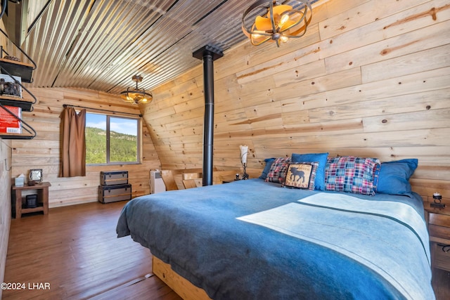 bedroom featuring wooden walls, wood-type flooring, lofted ceiling, a wood stove, and wood ceiling