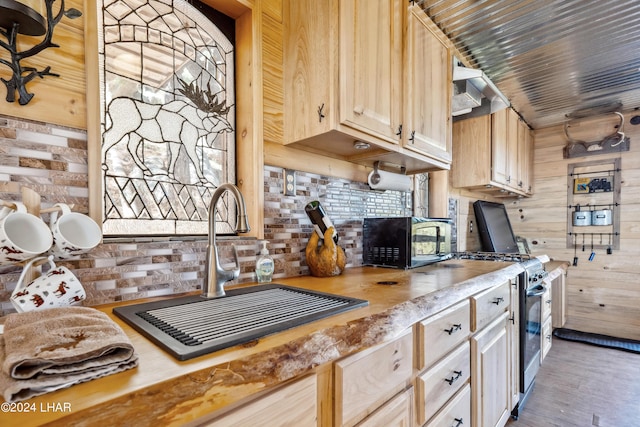 kitchen with dark wood-type flooring, light brown cabinetry, sink, high end stove, and decorative backsplash