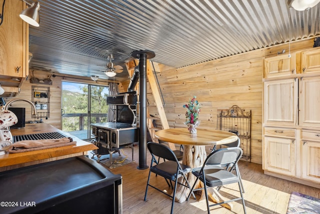 dining area with light wood-type flooring, wood walls, and a wood stove