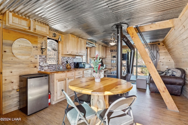 dining area with sink, light wood-type flooring, ceiling fan, and wood walls