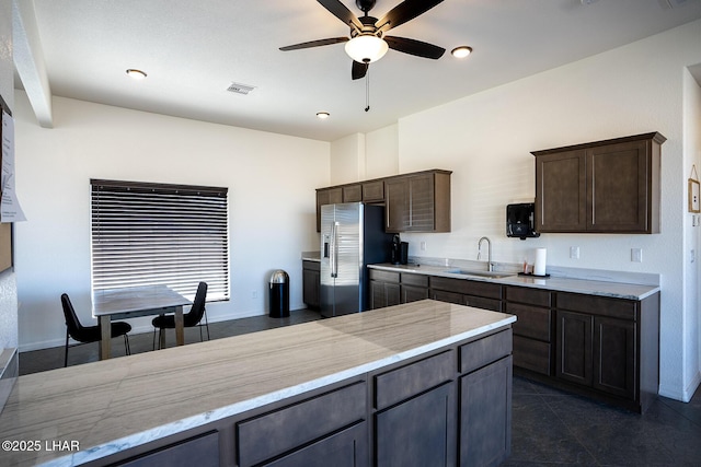 kitchen with sink, stainless steel fridge with ice dispenser, dark brown cabinets, dark tile patterned floors, and ceiling fan