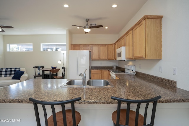 kitchen featuring white appliances, kitchen peninsula, and sink