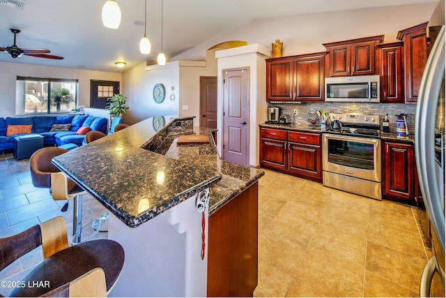 2930 Poseidon Ln, Lake Havasu City, AZ 86404 - kitchen featuring stainless steel appliances, reddish brown cabinets, vaulted ceiling, tasteful backsplash, and open floor plan